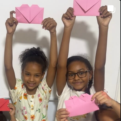 Children raising handmade heart envelopes in the air