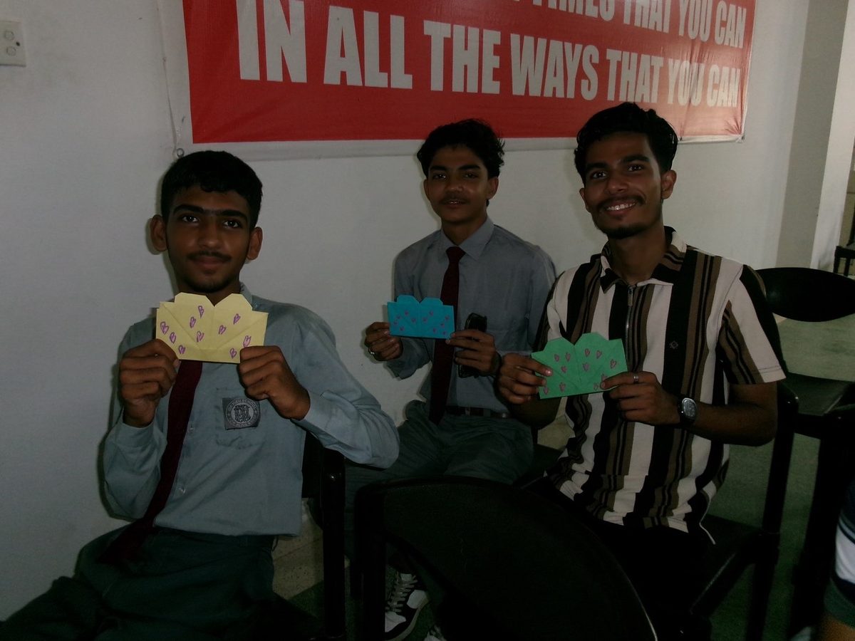 Students at IDA Rieu School holding pink and red heart envelopes outdoors.